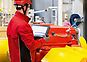 Man in red helmet and red jacket checking a red large gear unit